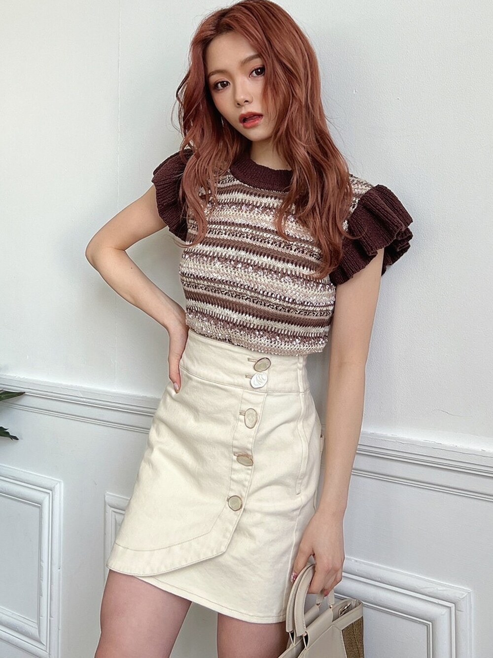 ベージュ系のハンドバッグ、その他のニット/セーター、ホワイト系のスカートを着用したレディースの春コーディネートの2枚目の写真