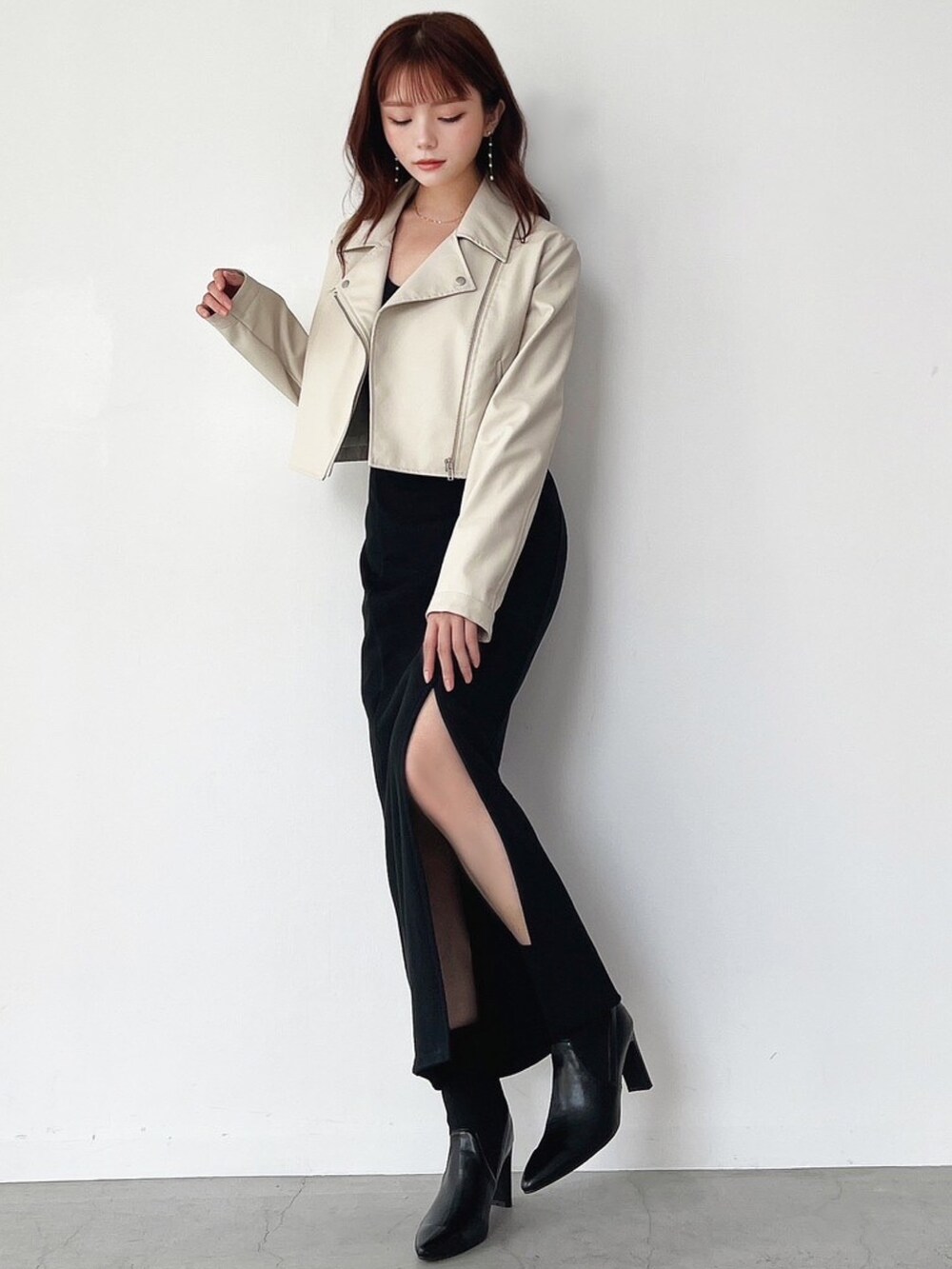 ホワイト系のライダースジャケット、ブラック系のワンピース、ゴールド系のピアス（両耳用）を着用したレディースの秋コーディネートの3枚目の写真