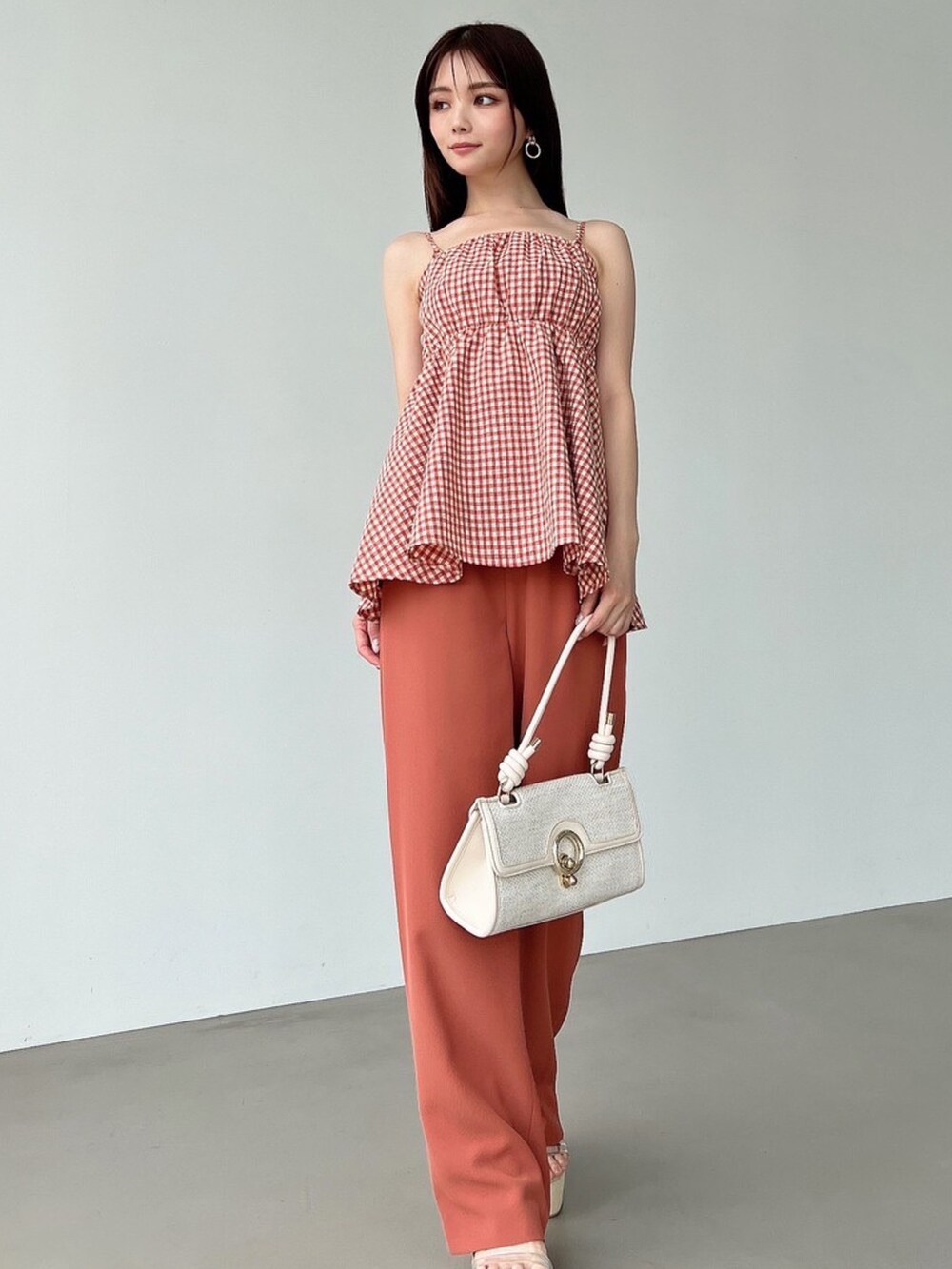 オレンジ系のキャミソール、オレンジ系のその他パンツ、ホワイト系のハンドバッグを着用したレディースの春コーディネートの4枚目の写真