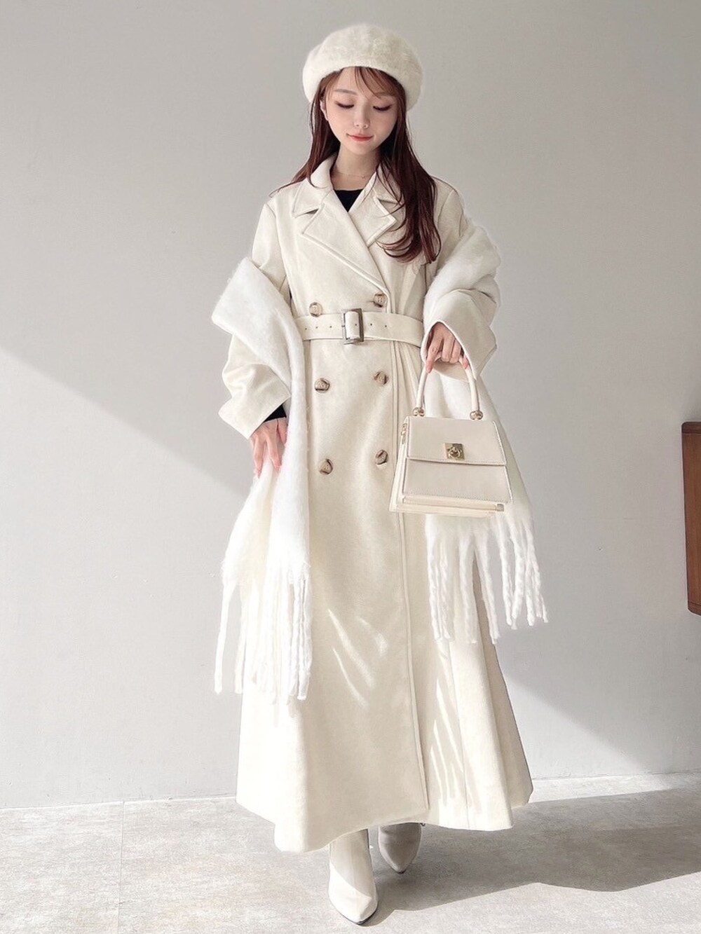 ホワイト系のチェスターコート、ホワイト系のハンドバッグ、ホワイト系のブーツを着用したレディースの秋コーディネートの2枚目の写真