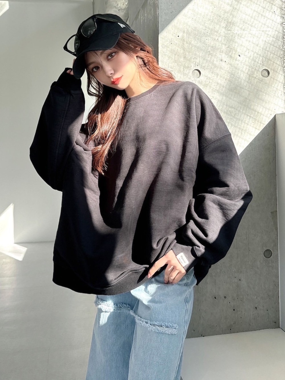 ブラック系のスウェット、ブルー系のデニムパンツを着用したレディースの春コーディネートの5枚目の写真