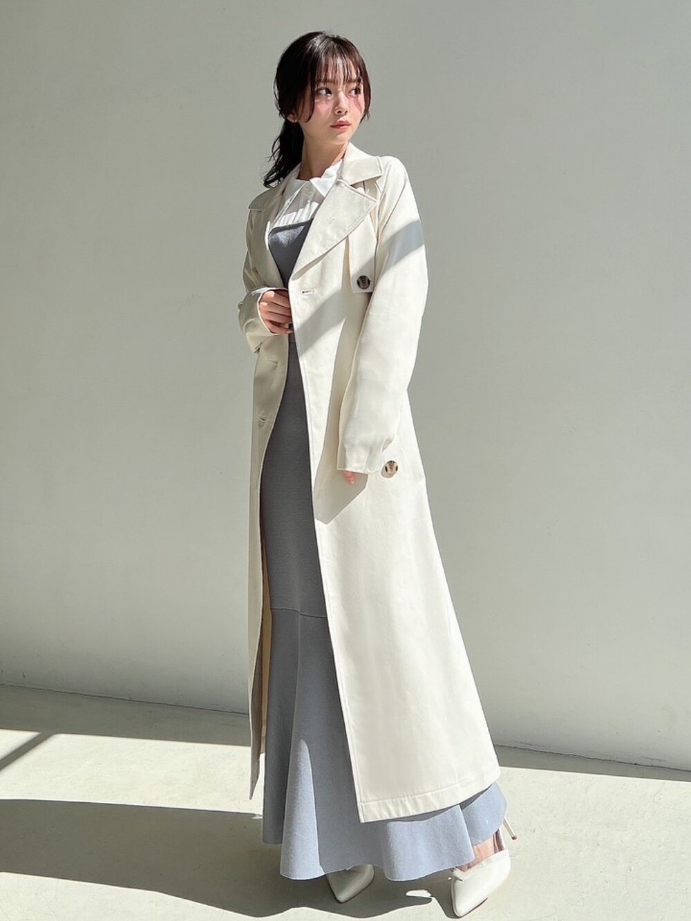 ブルー系のワンピース、ホワイト系のトレンチコートを着用したレディースの冬コーディネートの5枚目の写真