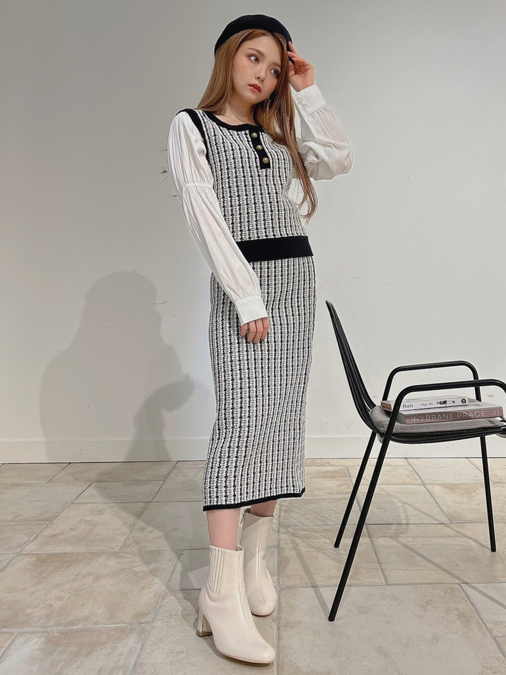 ブラック系のベスト、ホワイト系のブーツ、ブラック系のスカートを着用したレディースの秋コーディネートの4枚目の写真