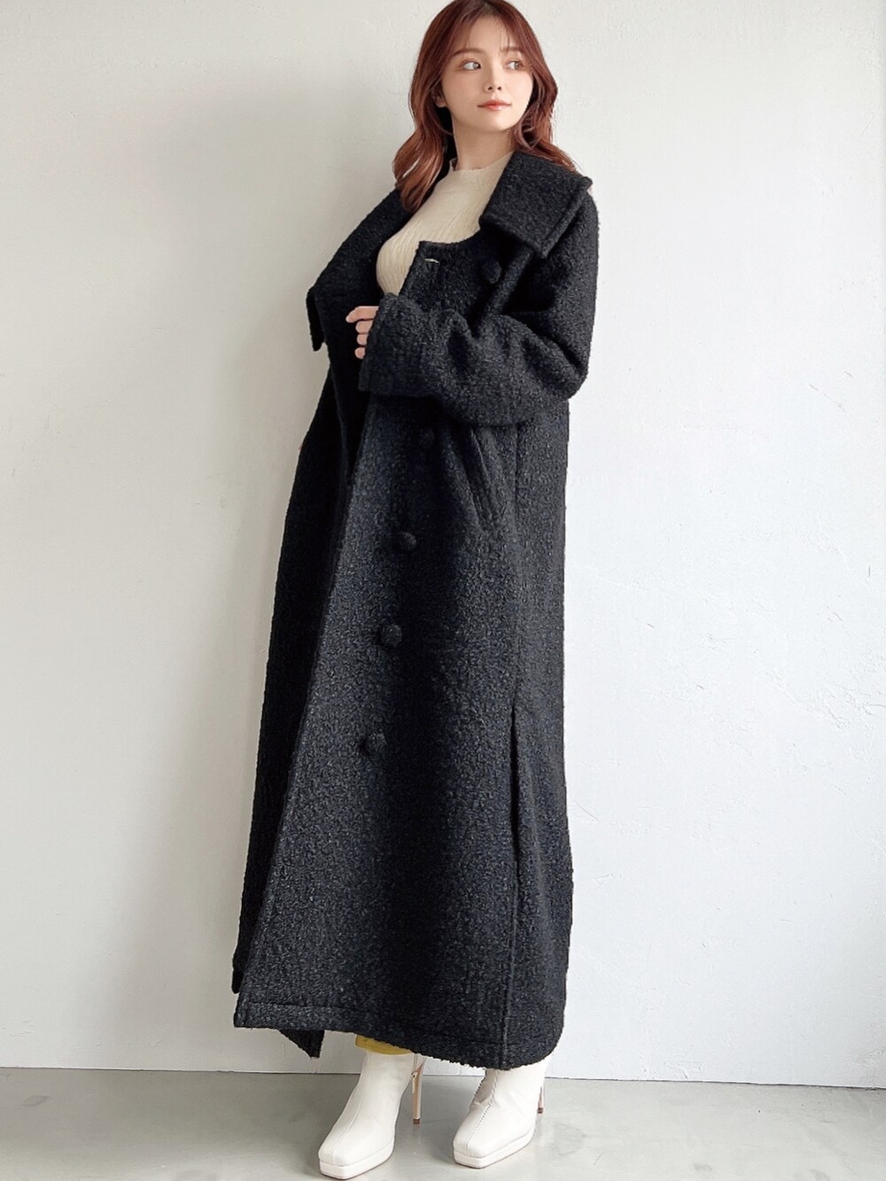 ブラウン系のスカート、ホワイト系のニット/セーター、ブラック系のチェスターコートを着用したレディースの冬コーディネートの2枚目の写真