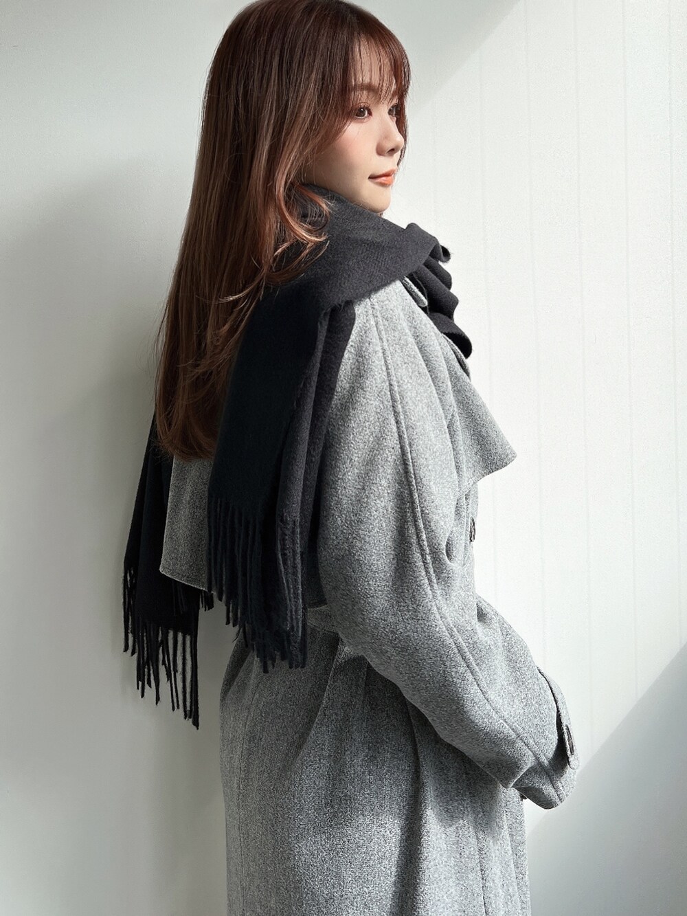 グレー系のトレンチコート、ブラック系のブーツ、ブラック系のストール/ショールを着用したレディースの秋コーディネートの4枚目の写真