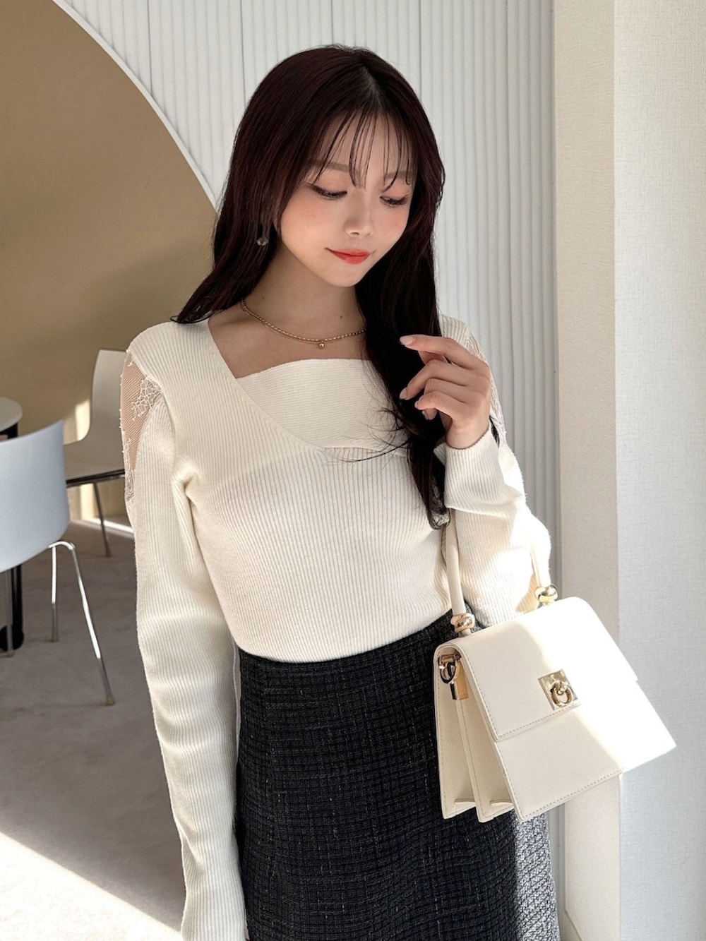 ホワイト系のニット/セーター、ブラック系のスカート、ホワイト系のハンドバッグを着用したレディースの冬コーディネートの4枚目の写真