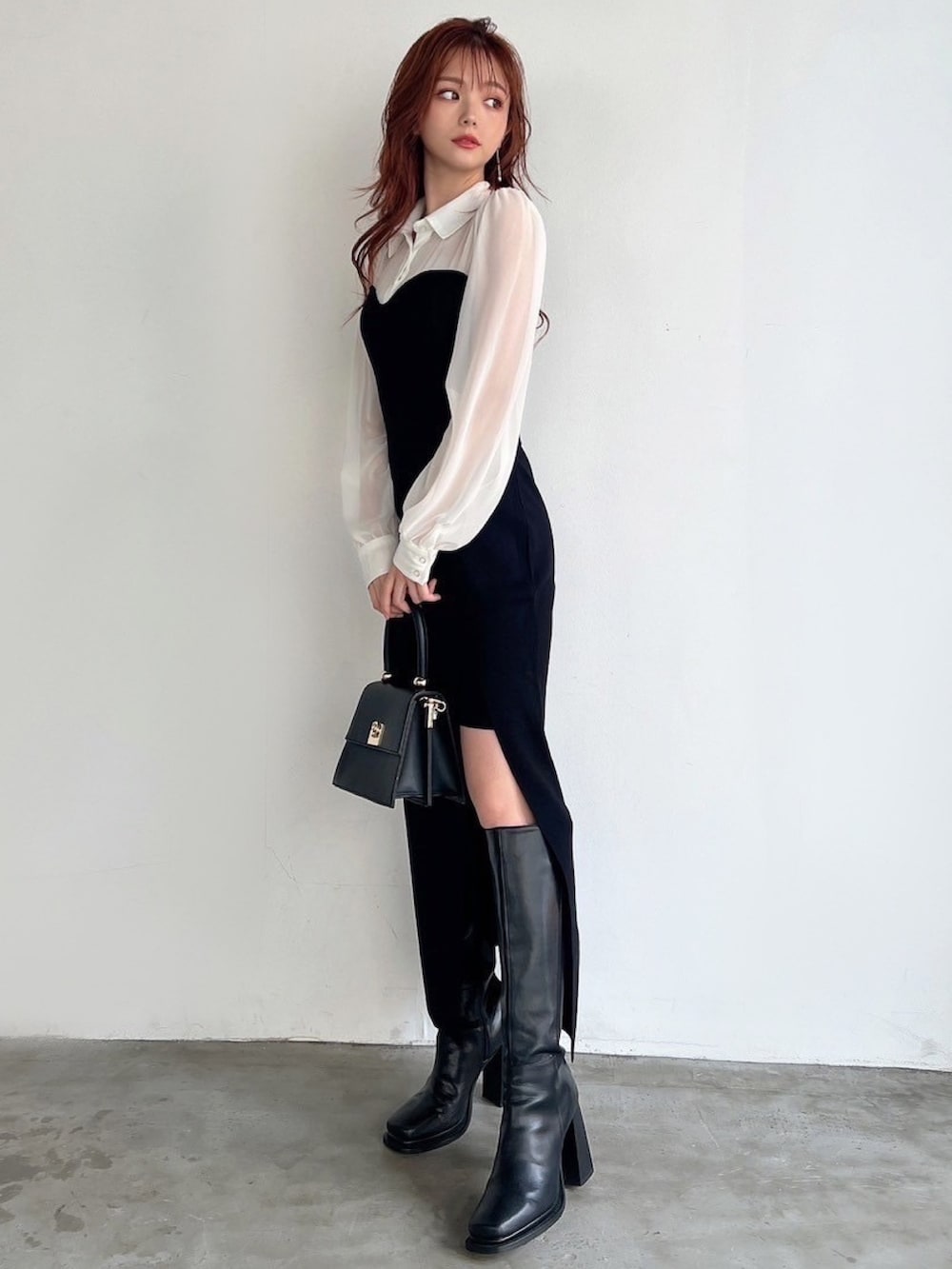 ブラック系のワンピース、ブラック系のハンドバッグ、ブラック系のブーツを着用したレディースの秋コーディネートの2枚目の写真