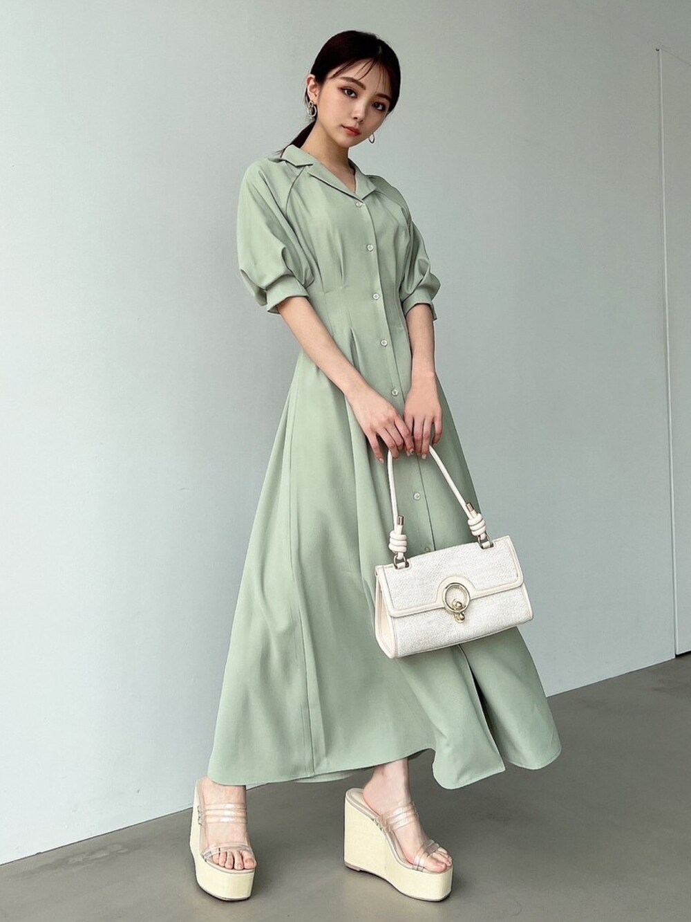 グリーン系のシャツワンピース、ホワイト系のサンダル、ホワイト系のハンドバッグを着用したレディースの春コーディネートの2枚目の写真