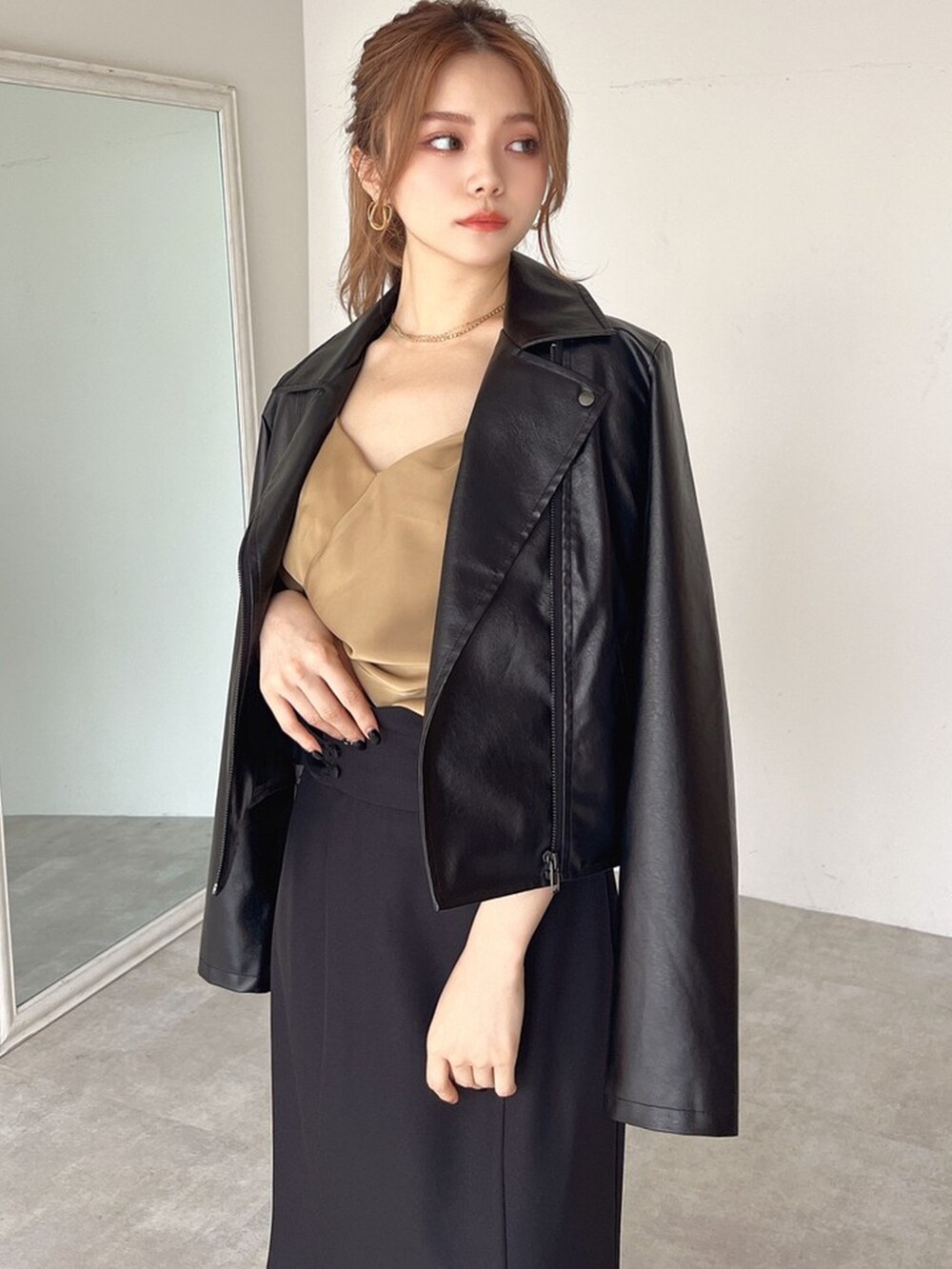 ブラック系のライダースジャケット、イエロー系のキャミソール、ブラック系のスカートを着用したレディースの夏コーディネートの3枚目の写真