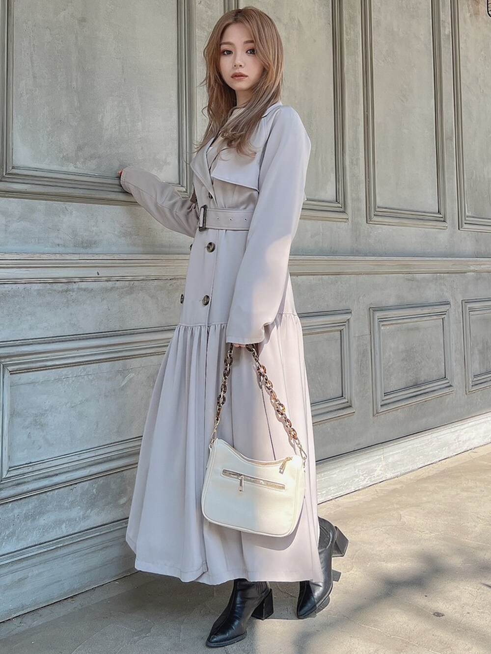 ホワイト系のトレンチコート、ホワイト系のニット/セーター、ブラウン系のブーツを着用したレディースの春コーディネートの3枚目の写真