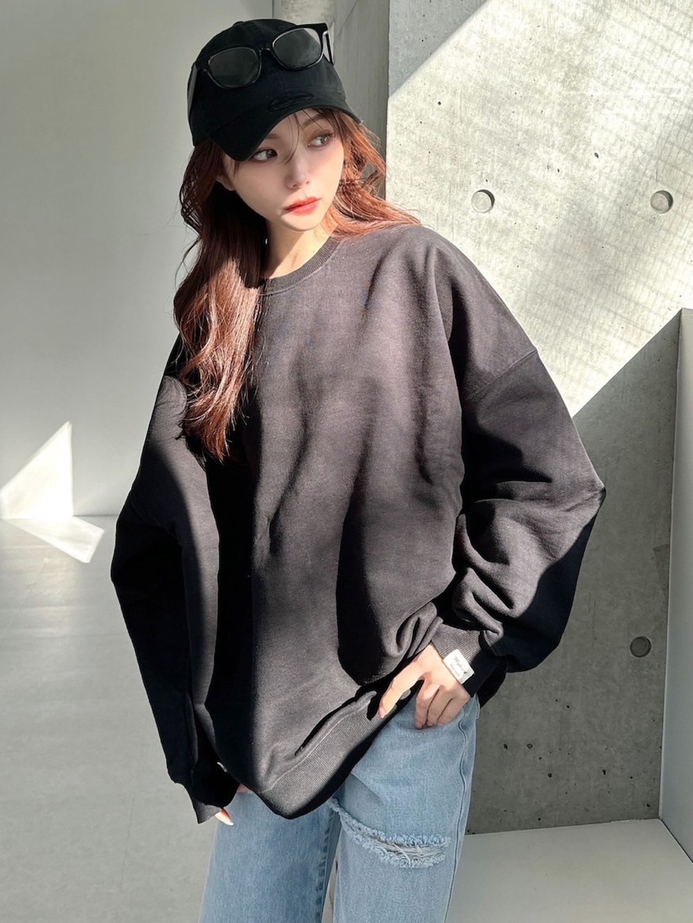 ブラック系のスウェット、ブルー系のデニムパンツを着用したレディースの春コーディネートの6枚目の写真