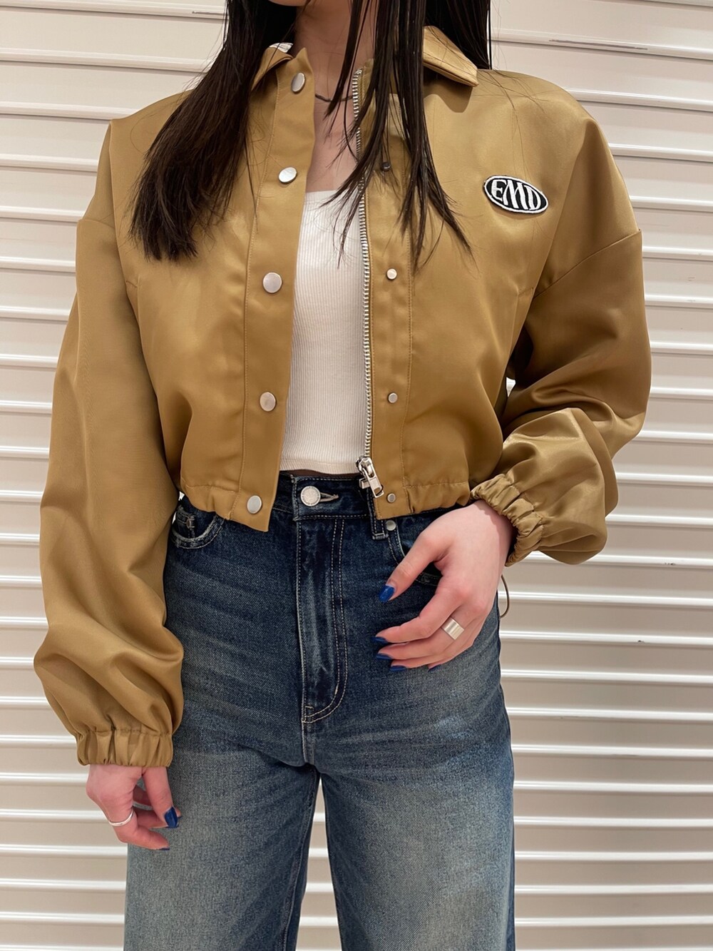 ベージュ系のブルゾン、ホワイト系のキャミソール、ブルー系のデニムパンツを着用したレディースの冬コーディネートの3枚目の写真