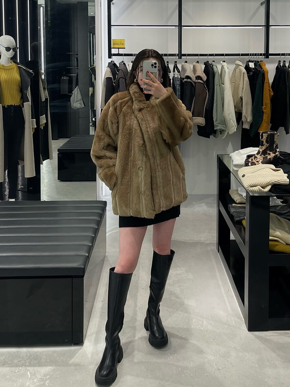 ブラック系のワンピース、ベージュ系のその他アウター、ブラック系のブーツを着用したレディースの冬コーディネートの3枚目の写真