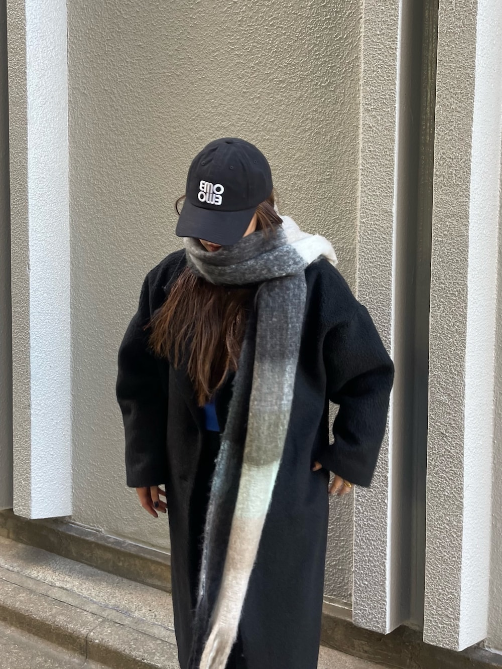 ブラック系のチェスターコート、ブラック系のデニムパンツ、ブラック系のマフラーを着用したレディースの冬コーディネートの5枚目の写真