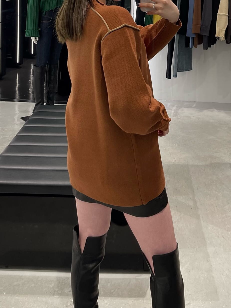 オレンジ系のニット/セーター、ブラック系のブーツを着用したレディースの秋コーディネートの5枚目の写真