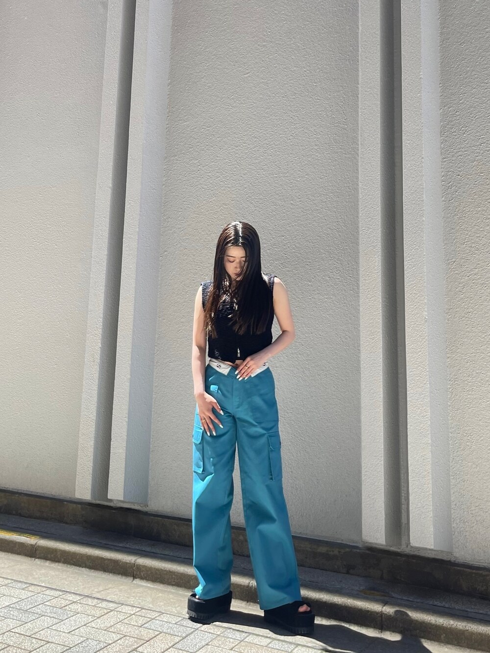 ブラック系のベスト、ブルー系のカーゴパンツ、ブラック系のサンダルを着用したレディースの夏コーディネートの2枚目の写真