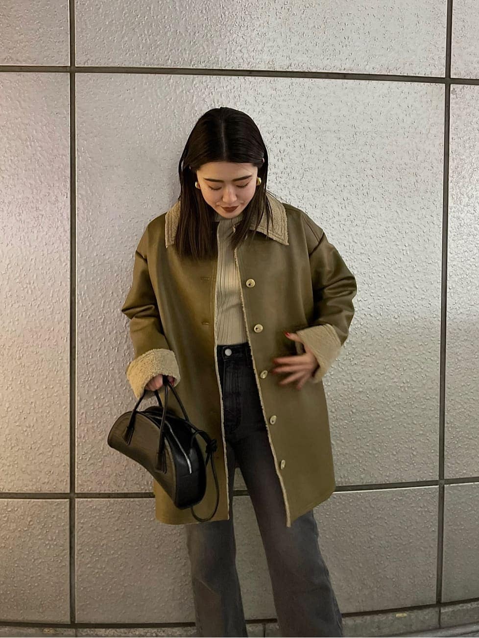 ブラック系のハンドバッグ、ベージュ系のムートンコート、ホワイト系のニット/セーターを着用したレディースの冬コーディネートの7枚目の写真