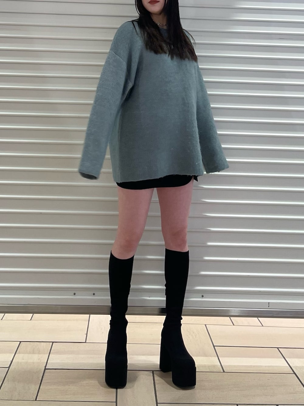 ブルー系のニット/セーター、ブラック系のスカート、ブラック系のブーツを着用したレディースの冬コーディネートの2枚目の写真