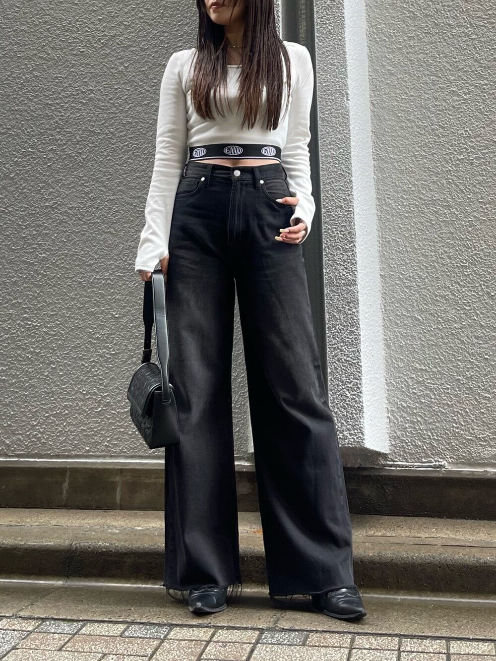 ホワイト系のTシャツ/カットソー、ブラック系のデニムパンツ、ブラック系のハンドバッグを着用したレディースの秋コーディネートの3枚目の写真
