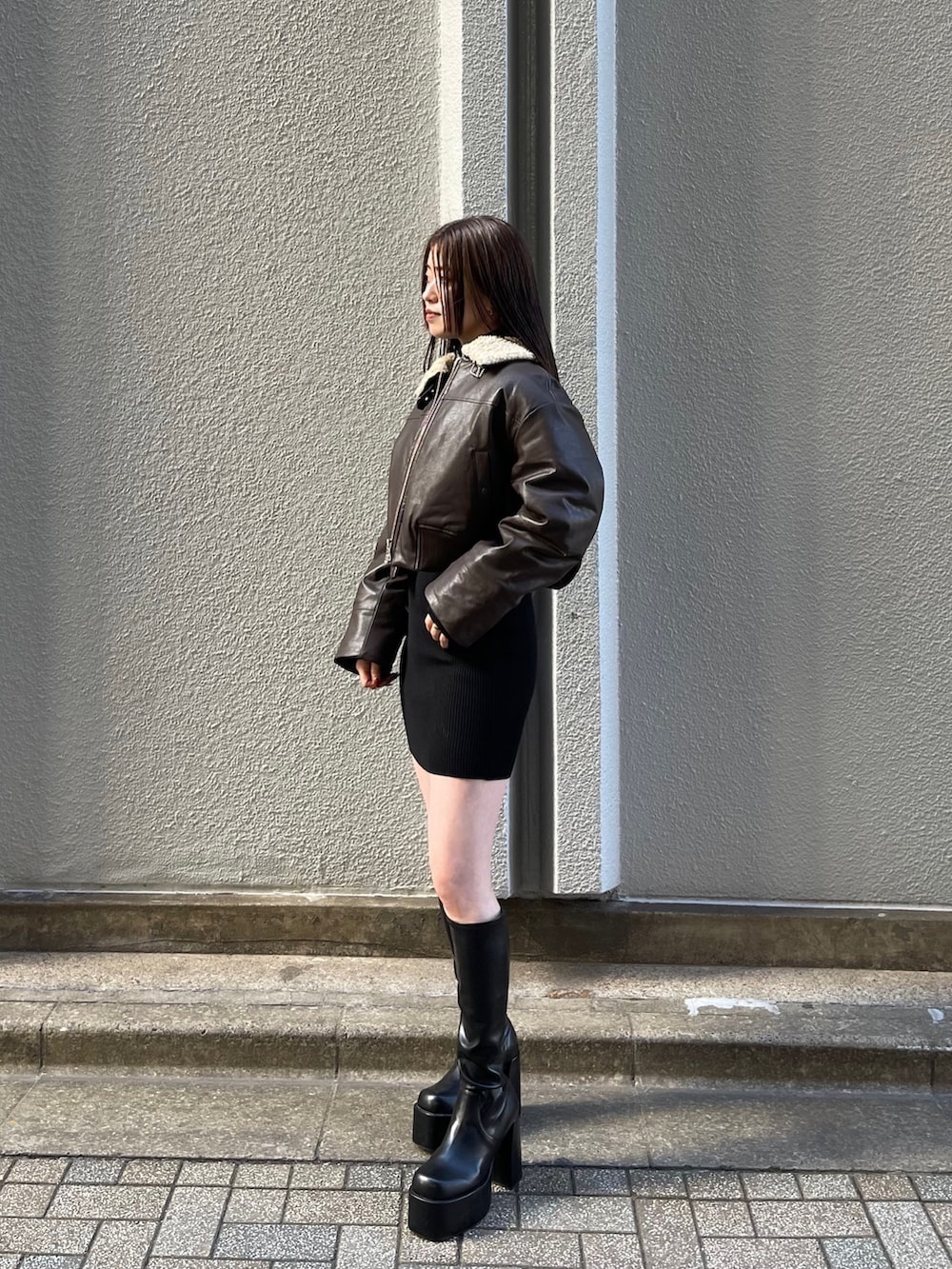 ブラウン系のブルゾン、ブラック系のワンピース、ブラック系のブーツを着用したレディースの秋コーディネートの2枚目の写真