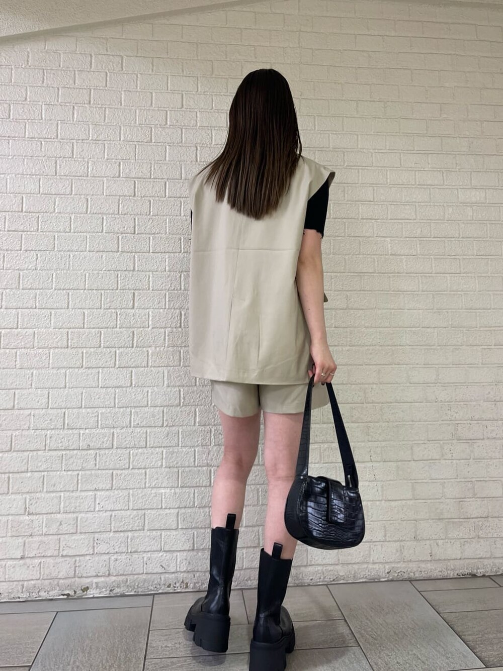 ベージュ系のベスト、ベージュ系のその他パンツ、ブラック系のブーツを着用したレディースの夏コーディネートの3枚目の写真