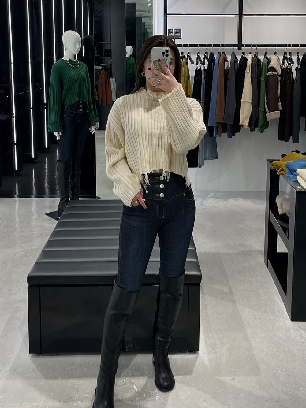 ブルー系のデニムパンツ、ブラック系のブーツ、ホワイト系のニット/セーターを着用したレディースの秋コーディネートの3枚目の写真