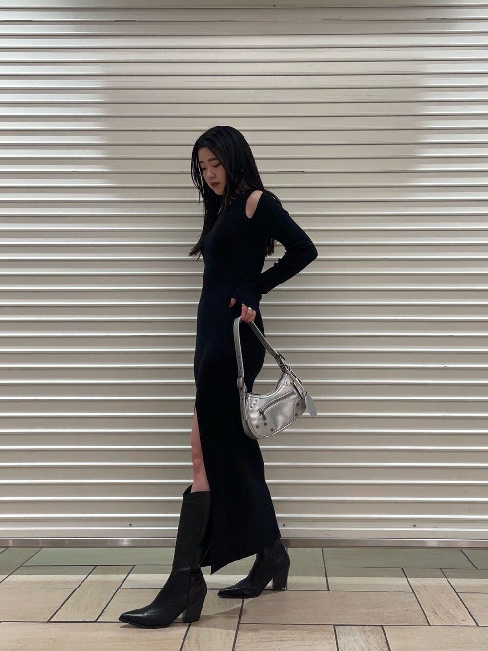 ブラック系のワンピース、シルバー系のハンドバッグ、ブラック系のブーツを着用したレディースの春コーディネートの3枚目の写真