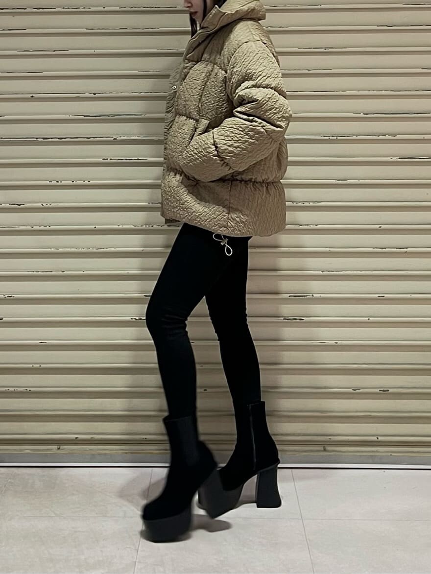 ブラック系のデニムパンツ、ブラック系のブーツ、ベージュ系のダウンジャケット/コートを着用したレディースの秋コーディネートの3枚目の写真