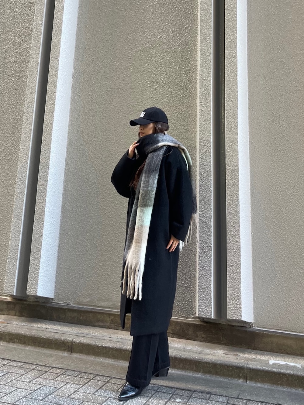 ブラック系のチェスターコート、ブラック系のデニムパンツ、ブラック系のマフラーを着用したレディースの冬コーディネートの2枚目の写真