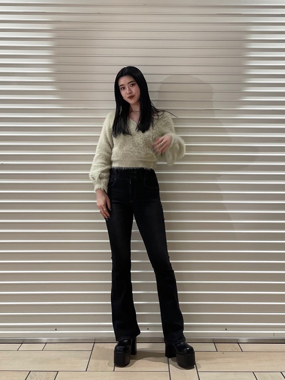 ブラック系のデニムパンツ、ホワイト系のニット/セーター、ブラック系のブーツを着用したレディースの冬コーディネートの2枚目の写真