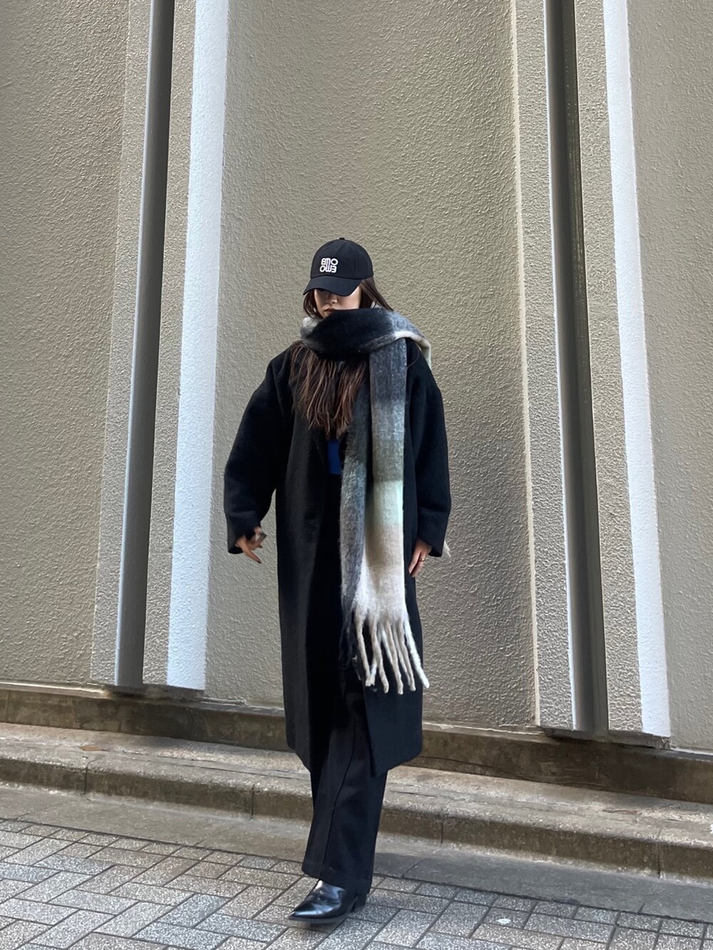 ブラック系のチェスターコート、ブラック系のデニムパンツ、ブラック系のマフラーを着用したレディースの冬コーディネートの3枚目の写真