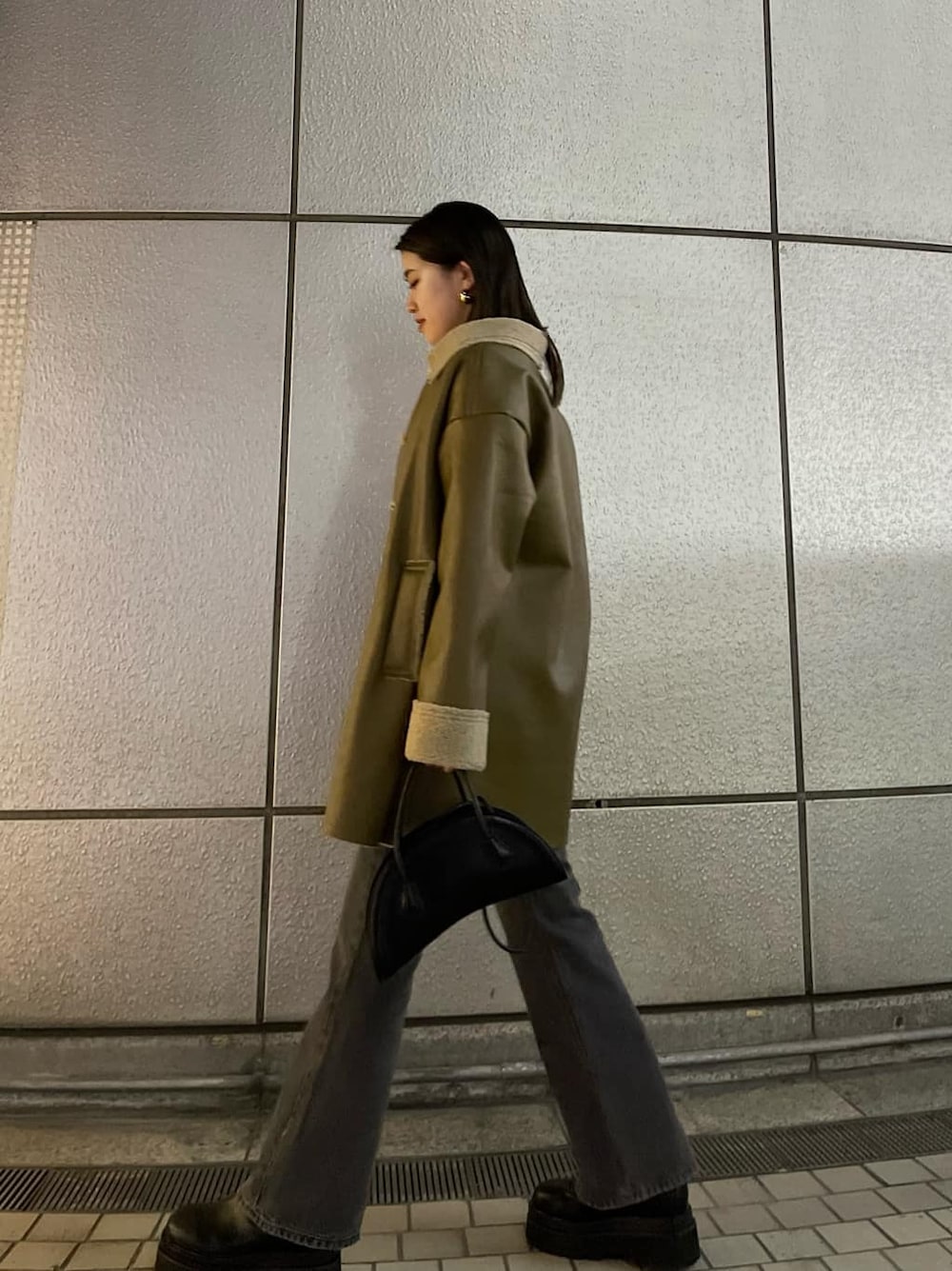 ブラック系のハンドバッグ、ベージュ系のムートンコート、ホワイト系のニット/セーターを着用したレディースの冬コーディネートの5枚目の写真