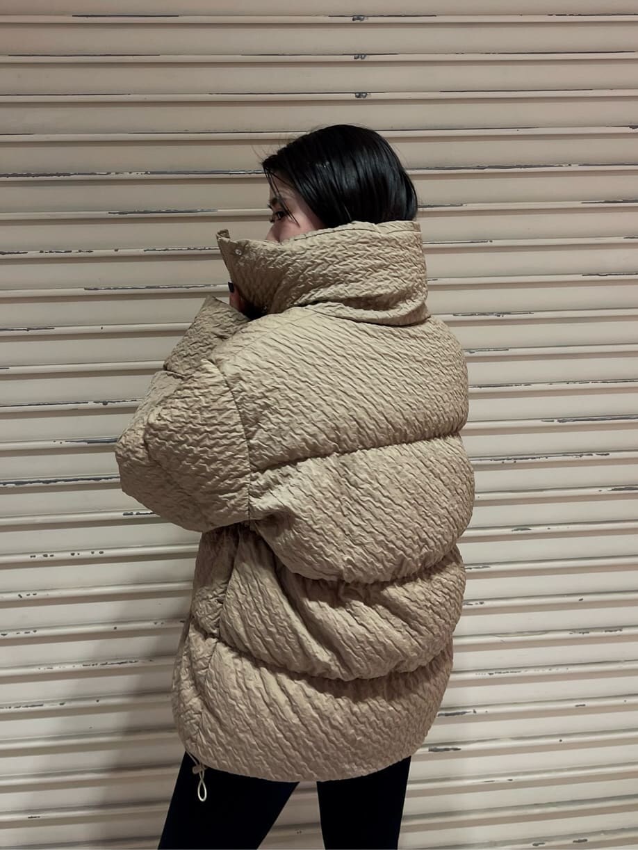 ブラック系のデニムパンツ、ブラック系のブーツ、ベージュ系のダウンジャケット/コートを着用したレディースの秋コーディネートの4枚目の写真