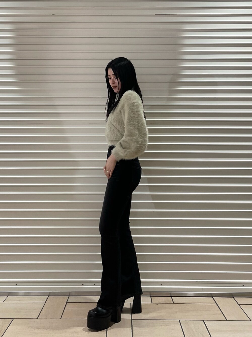 ブラック系のデニムパンツ、ホワイト系のニット/セーター、ブラック系のブーツを着用したレディースの冬コーディネートの3枚目の写真