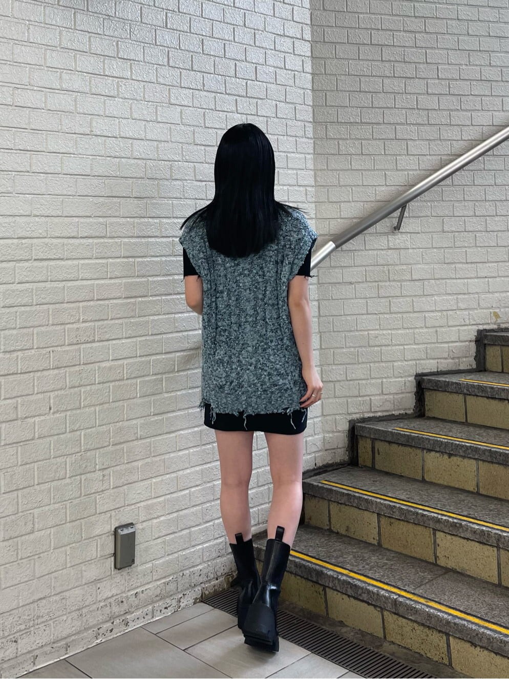 ブラック系のスカート、ブラック系のブーツ、ブラック系のニット/セーターを着用したレディースの夏コーディネートの4枚目の写真