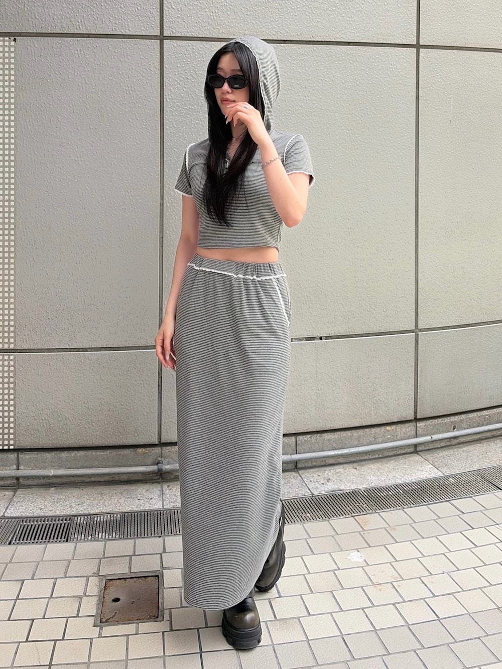 グレー系のスカート、グレー系のTシャツ/カットソー、ブラック系のブーツを着用したレディースの春コーディネートの2枚目の写真