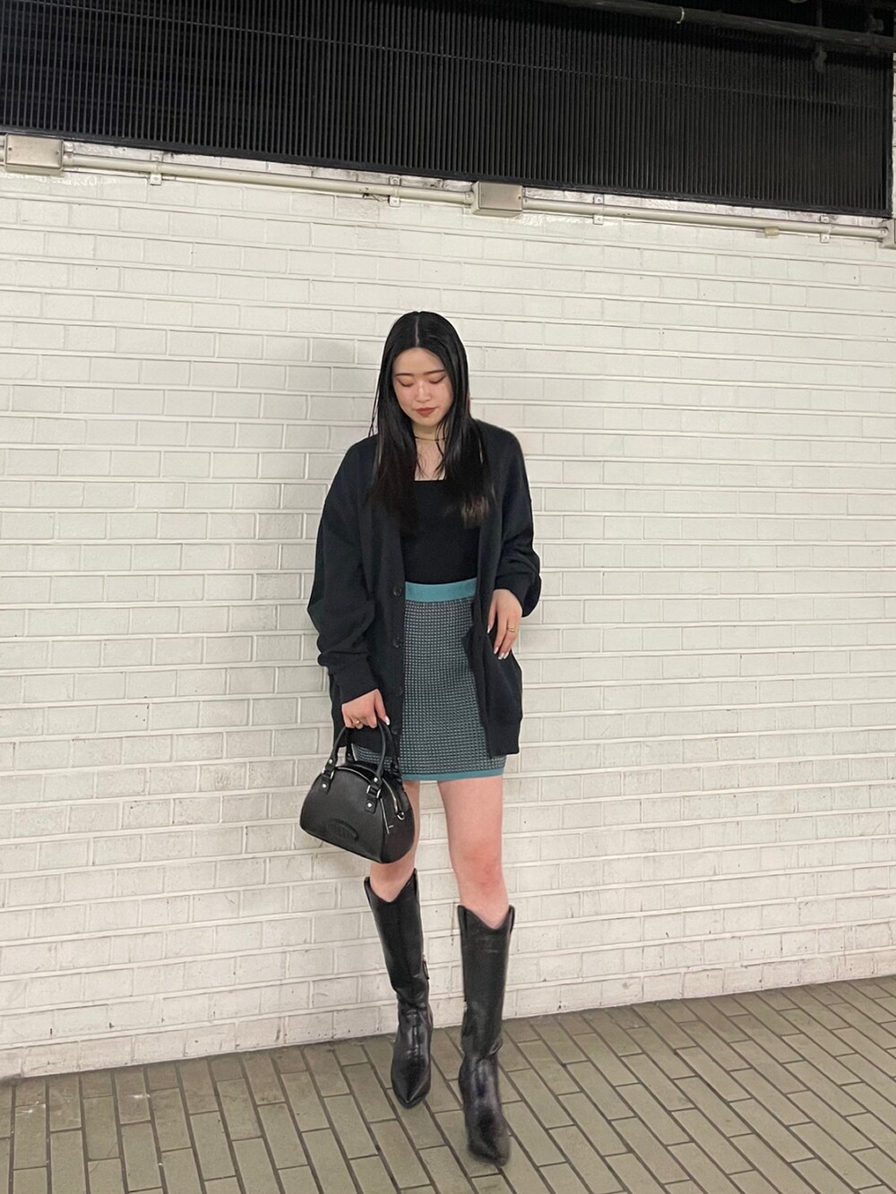 ブラック系のブーツ、ブルー系のスカート、ブラック系のカーディガン/ボレロを着用したレディースの春コーディネートの3枚目の写真
