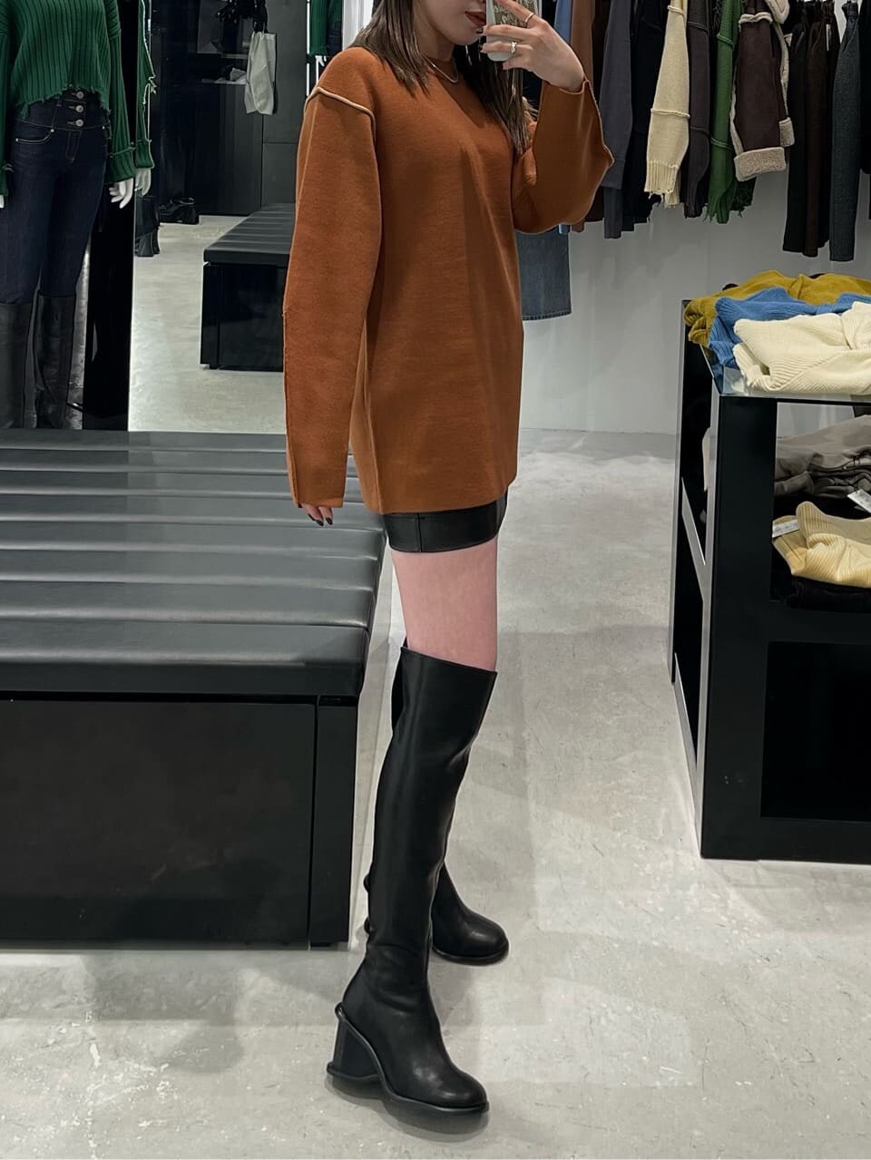 オレンジ系のニット/セーター、ブラック系のブーツを着用したレディースの秋コーディネートの2枚目の写真