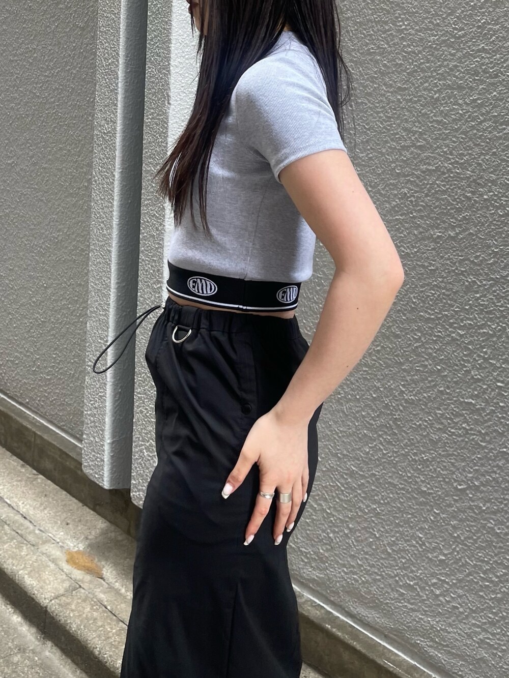 ブラック系のスカート、グレー系のTシャツ/カットソー、ブラック系のブーツを着用したレディースの春コーディネートの3枚目の写真