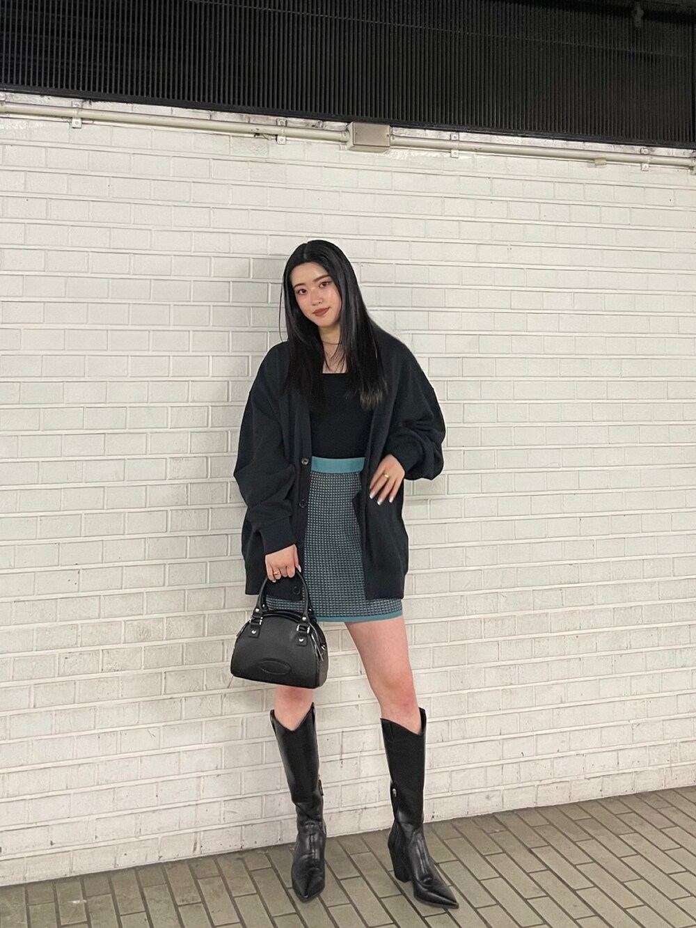 ブラック系のブーツ、ブルー系のスカート、ブラック系のカーディガン/ボレロを着用したレディースの春コーディネートの2枚目の写真