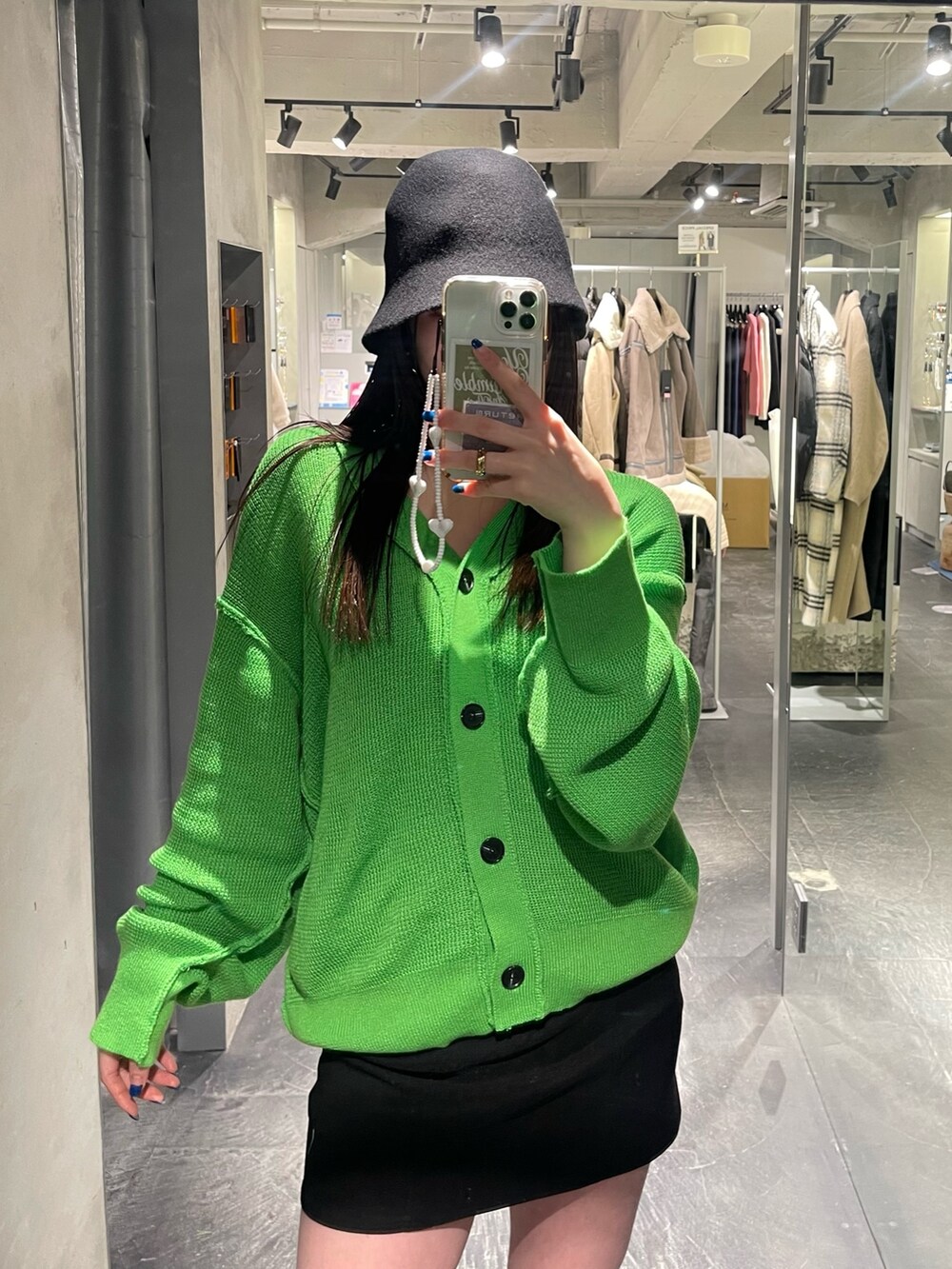 グリーン系のカーディガン/ボレロ、ブラック系のスカート、ブラック系のブーツを着用したレディースの冬コーディネートの3枚目の写真