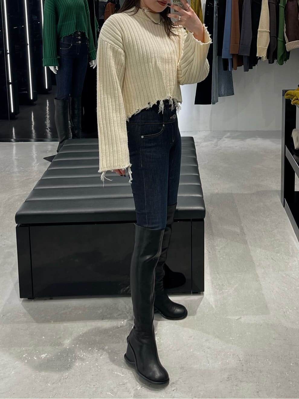 ブルー系のデニムパンツ、ブラック系のブーツ、ホワイト系のニット/セーターを着用したレディースの秋コーディネートの4枚目の写真