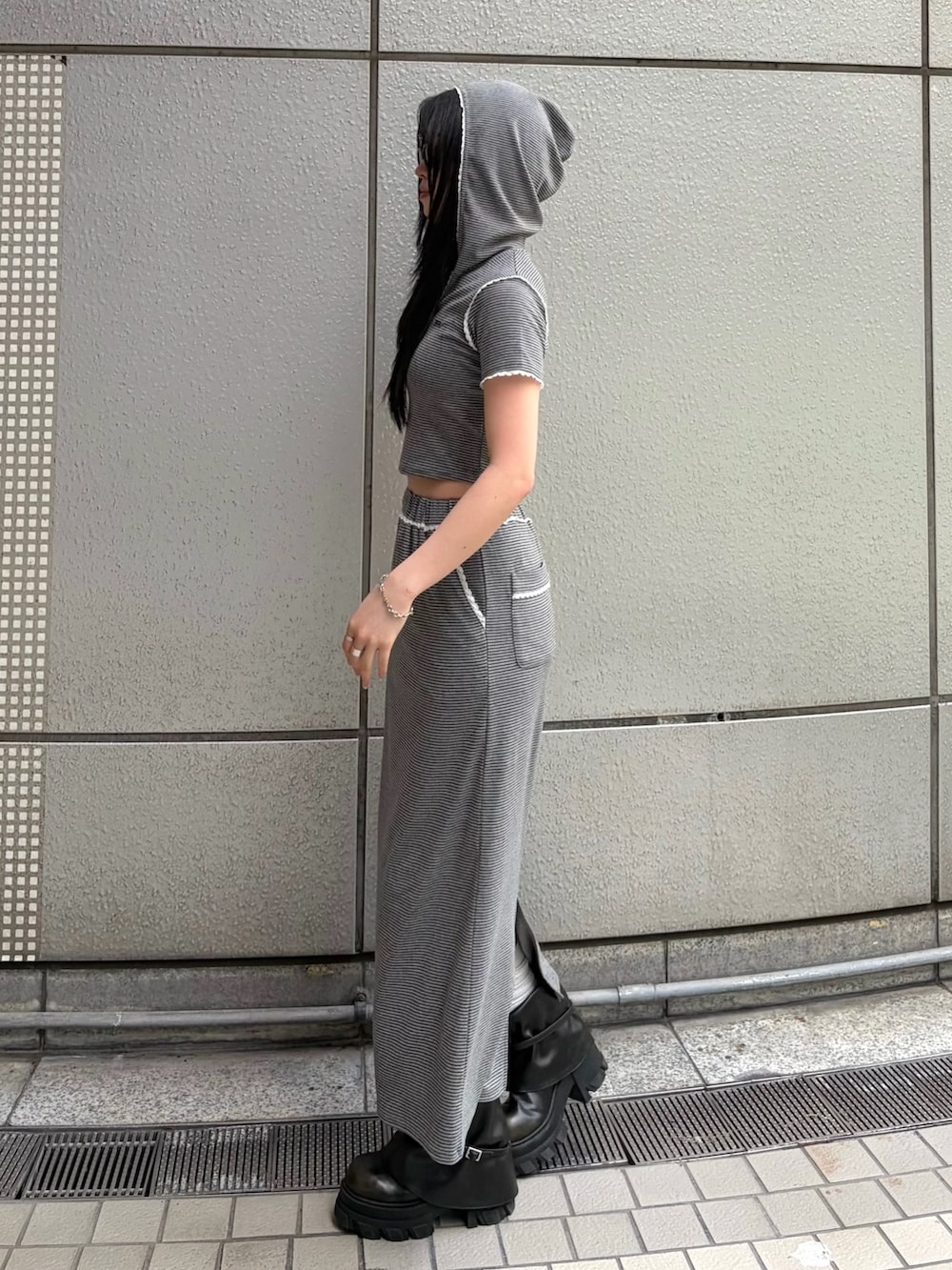 グレー系のスカート、グレー系のTシャツ/カットソー、ブラック系のブーツを着用したレディースの春コーディネートの5枚目の写真