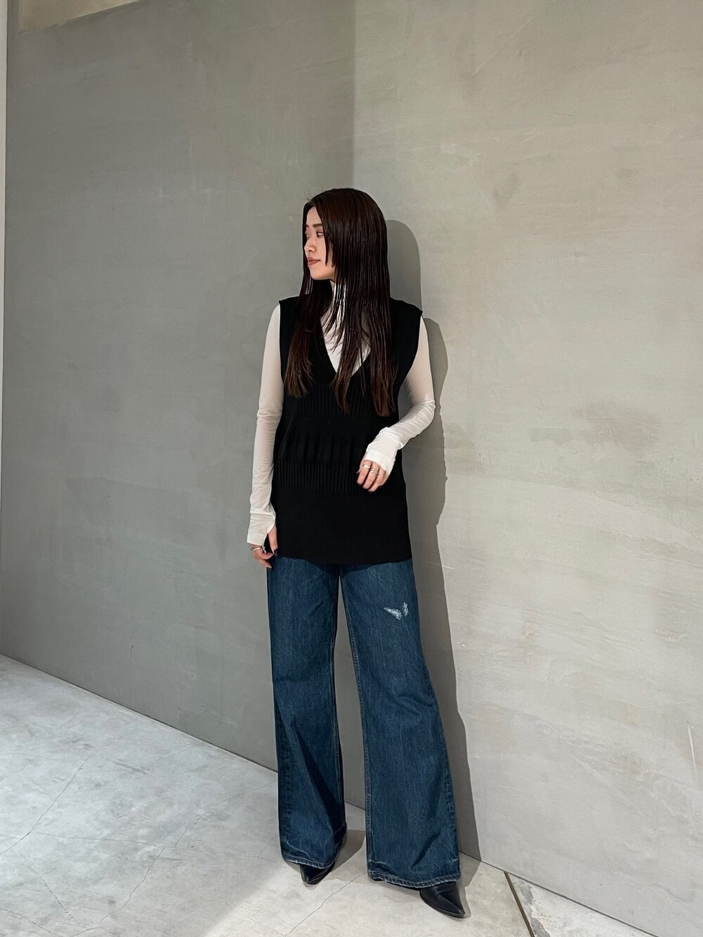 ブラック系のニット/セーター、ブルー系のデニムパンツ、ホワイト系のTシャツ/カットソーを着用したレディースの秋コーディネートの4枚目の写真