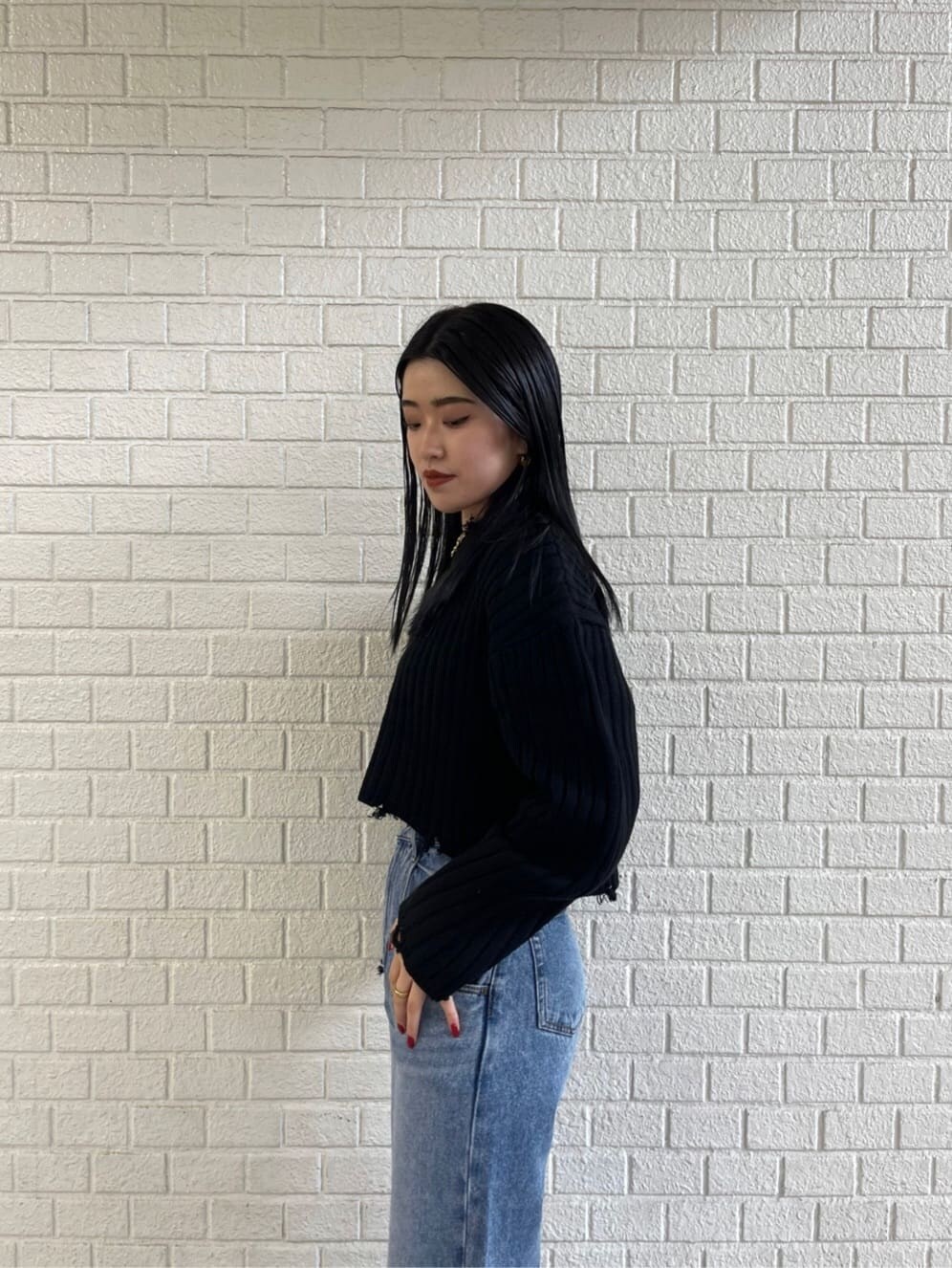 ブラック系のブーツ、ブルー系のデニムパンツ、ブラック系のニット/セーターを着用したレディースの秋コーディネートの4枚目の写真