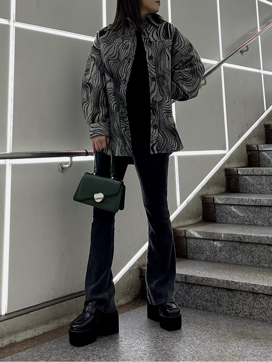 ブラック系のローファー、グリーン系のハンドバッグ、ブラック系のニット/セーターを着用したレディースの秋コーディネートの2枚目の写真