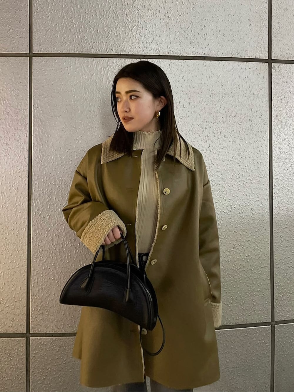 ブラック系のハンドバッグ、ベージュ系のムートンコート、ホワイト系のニット/セーターを着用したレディースの冬コーディネートの8枚目の写真