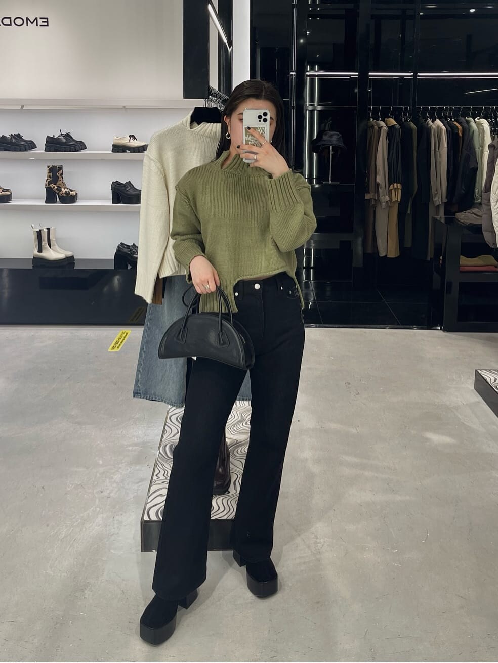 ブラック系のブーツ、ブラック系のデニムパンツ、ベージュ系のニット/セーターを着用したレディースの秋コーディネートの3枚目の写真