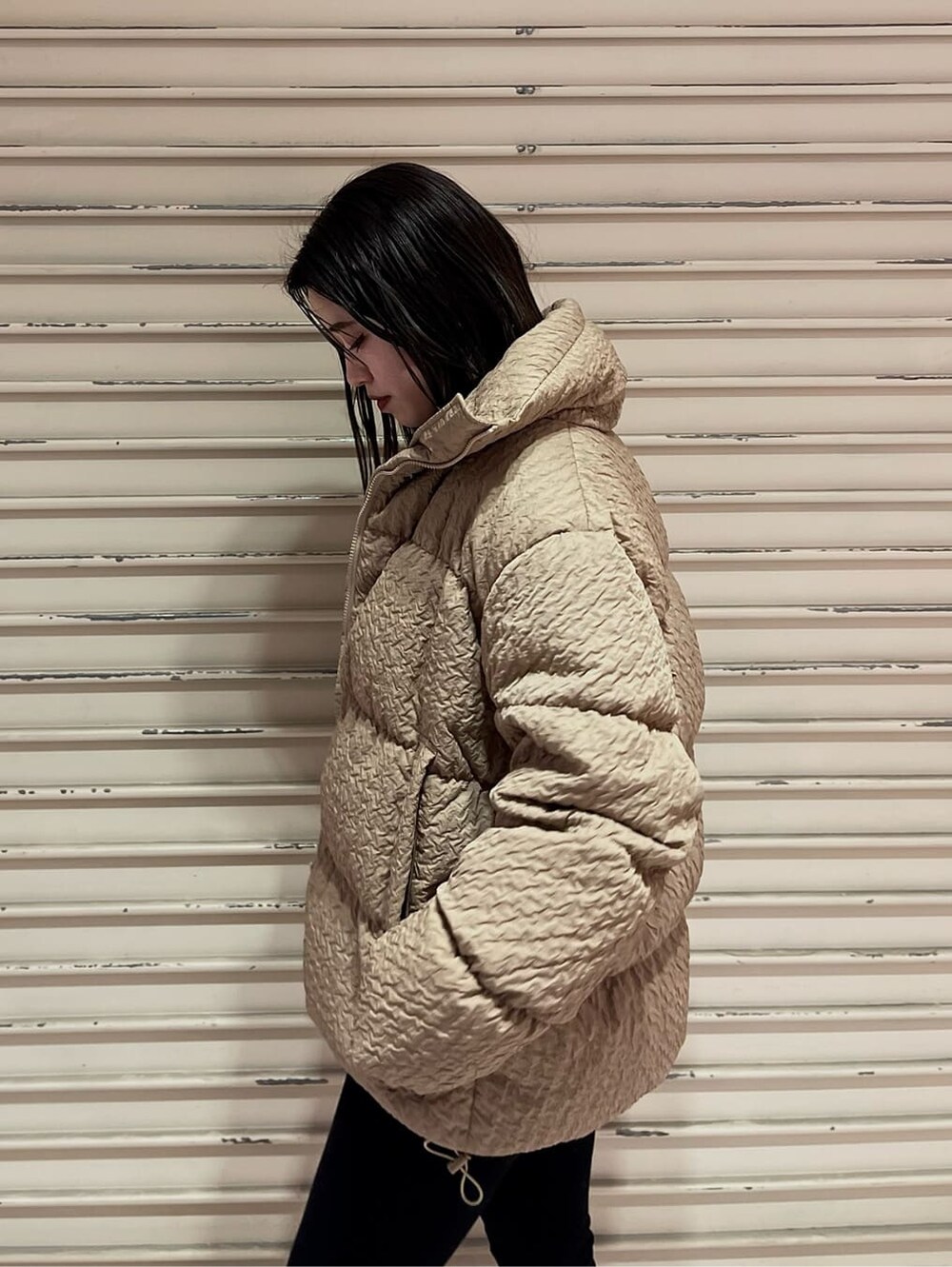 ブラック系のデニムパンツ、ブラック系のブーツ、ベージュ系のダウンジャケット/コートを着用したレディースの秋コーディネートの5枚目の写真