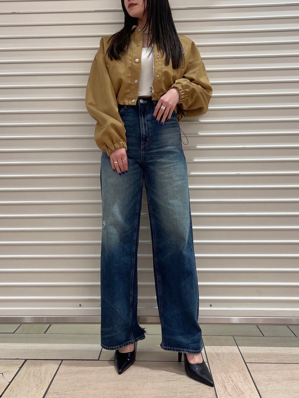 ベージュ系のブルゾン、ホワイト系のキャミソール、ブルー系のデニムパンツを着用したレディースの冬コーディネートの2枚目の写真